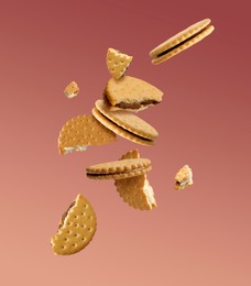 Image of Tasty broken sandwich cookies in air on brown gradient background