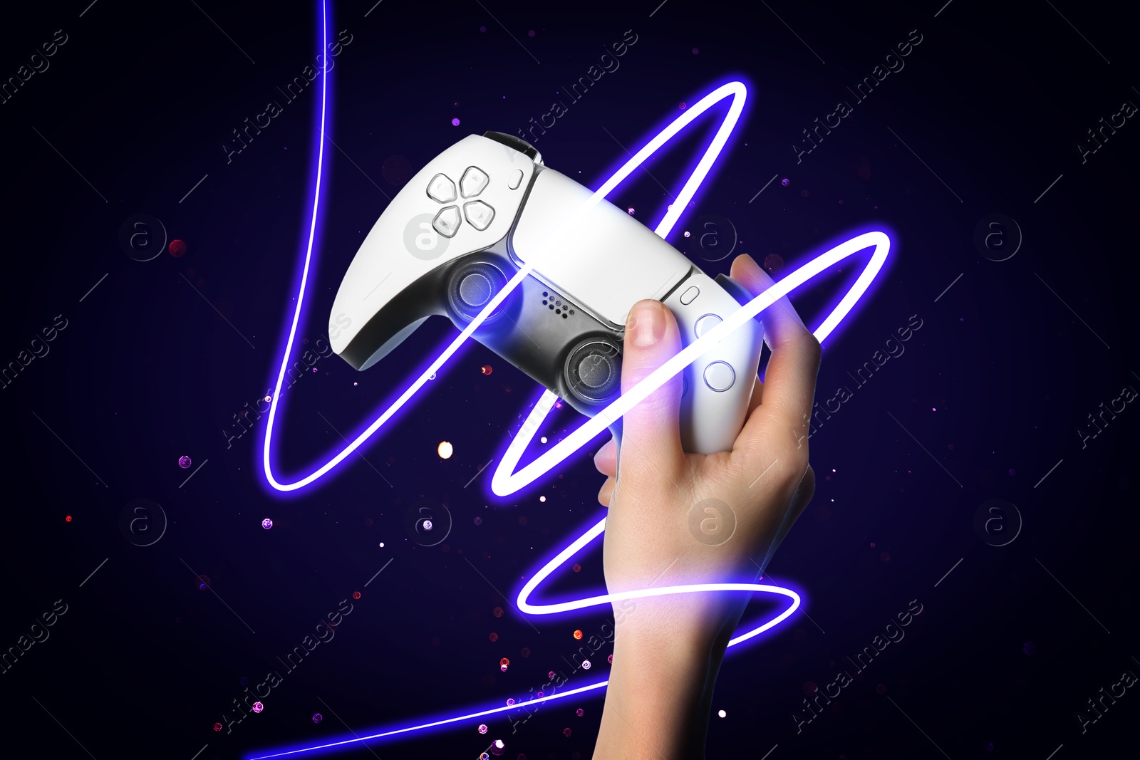 Image of Woman holding video game controller on dark blue gradient background, closeup. Glowing neon string of light around hand with device