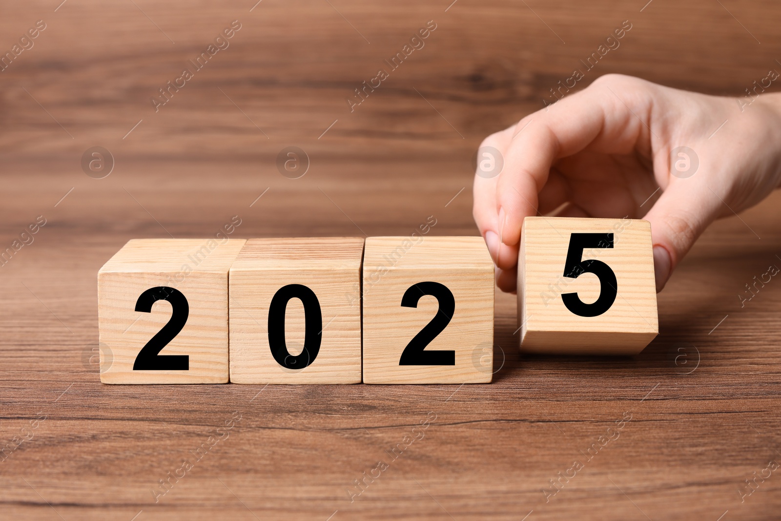 Image of 2025 New Year. Woman putting wooden cube with number 5 on table, closeup