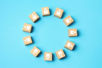 Image of Human resource. Circle of wooden cubes with human icons on light blue background, top view