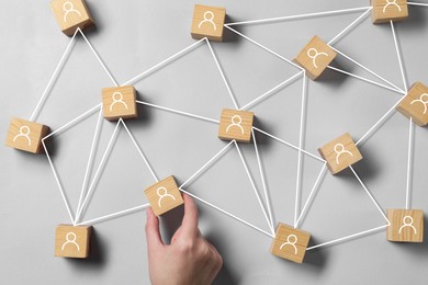 Image of Human resource. Woman with scheme of wooden cubes with human icons on light grey background, top view