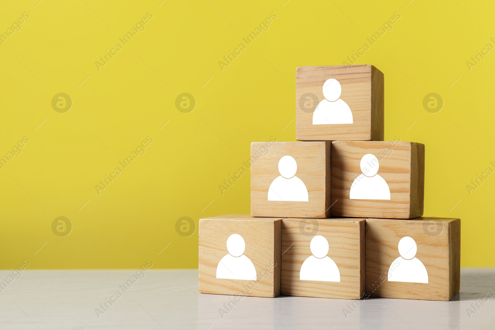 Image of Human resource. Pyramid of wooden cubes with human icons on yellow background, space for text