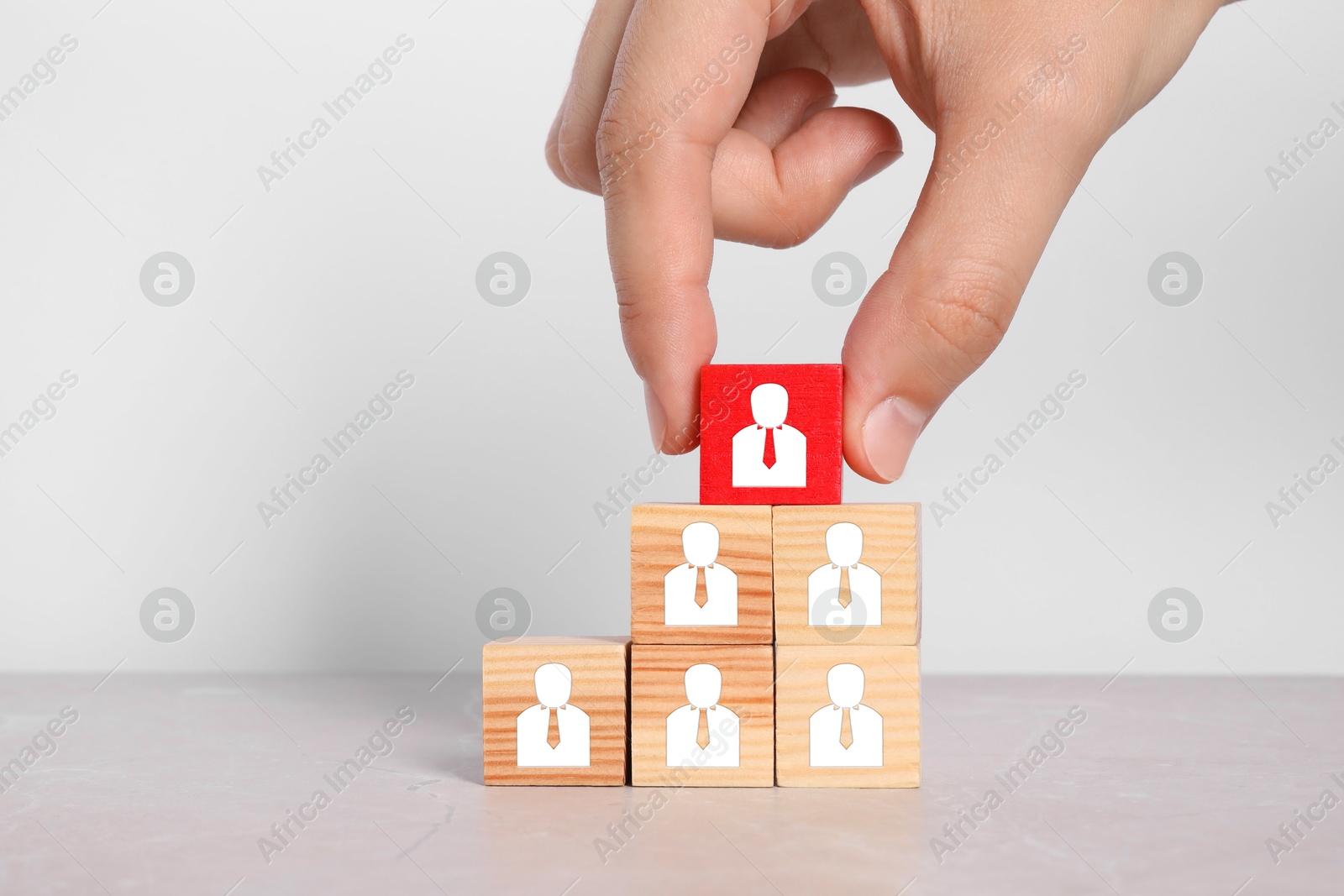 Image of Human resource. Woman stacking wooden cubes with human icons on white table, closeup