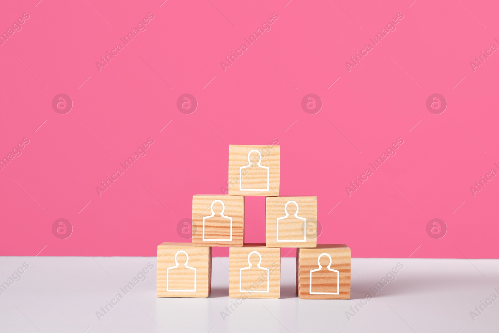 Image of Human resource. Pyramid of wooden cubes with human icons against pink background