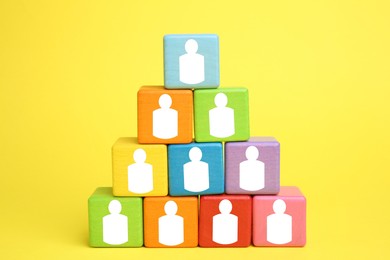 Image of Human resource. Pyramid of colorful cubes with human icons on yellow background