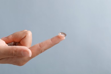 Photo of Woman holding color contact lens on light grey background, closeup