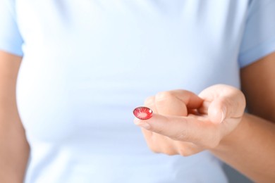 Photo of Woman holding one color contact lens, closeup