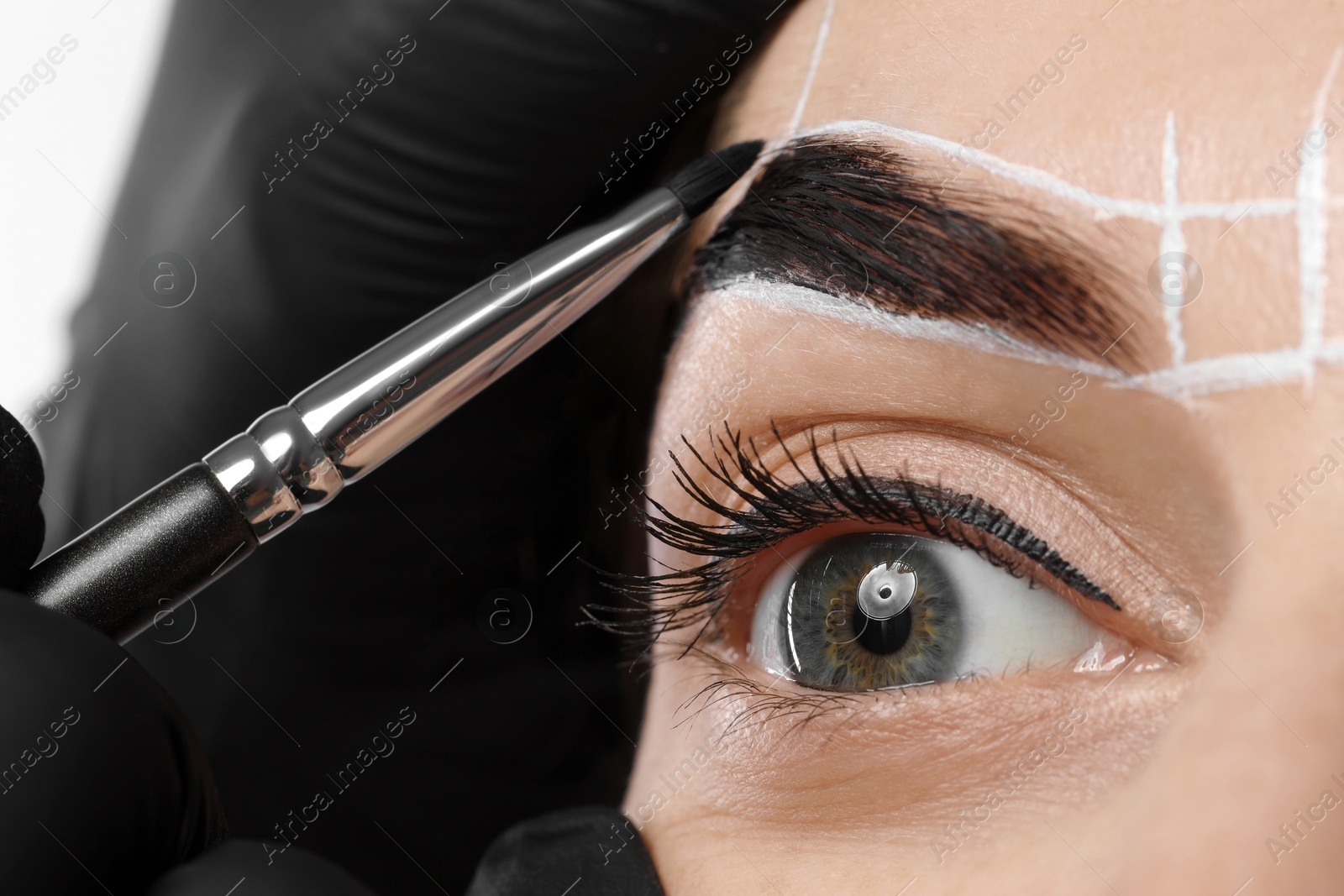 Photo of Young woman undergoing henna eyebrows dyeing procedure, closeup