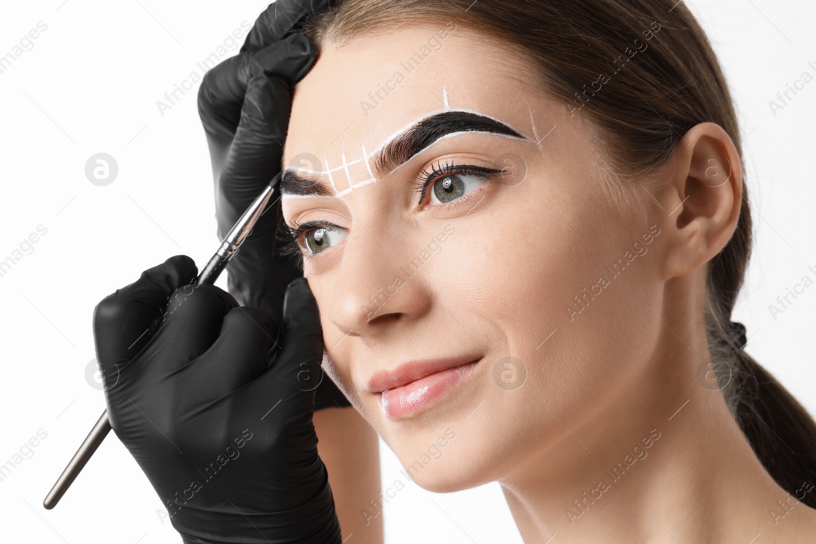 Photo of Young woman undergoing henna eyebrows dyeing procedure on light background, closeup