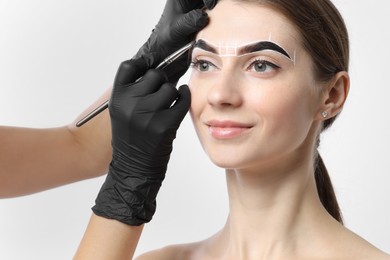 Photo of Young woman undergoing henna eyebrows dyeing procedure on white background, closeup