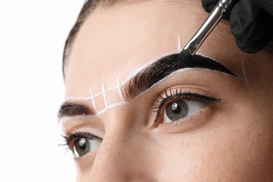 Photo of Young woman undergoing henna eyebrows dyeing on light background, closeup