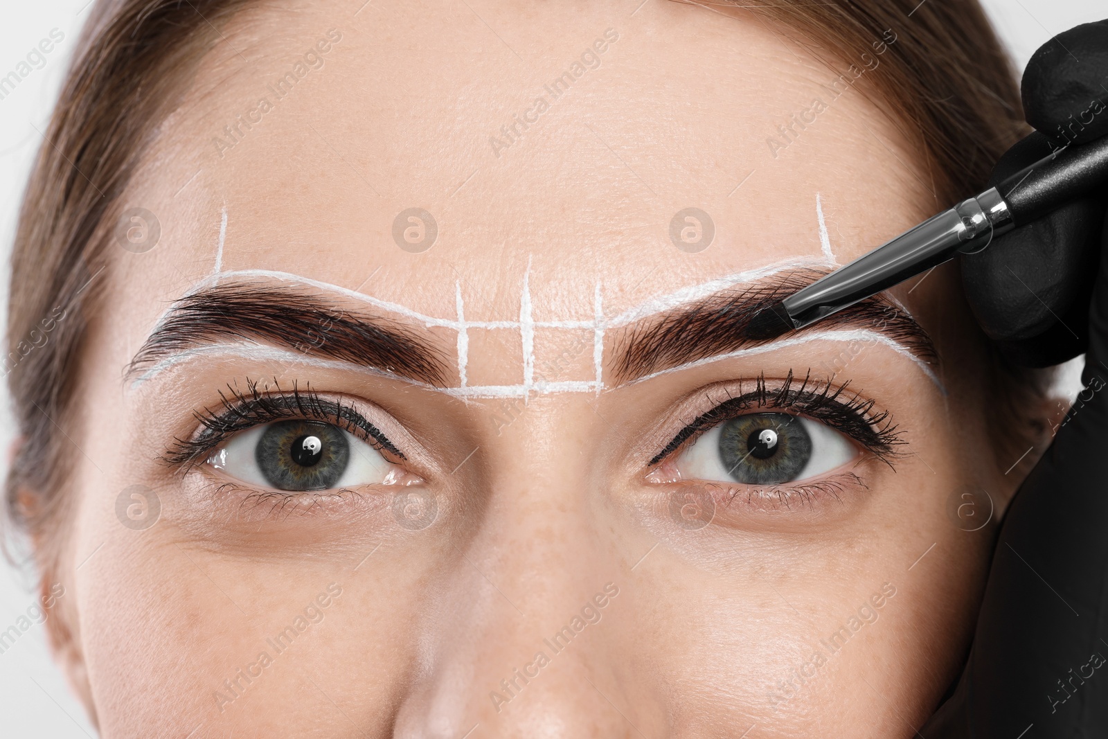 Photo of Young woman undergoing henna eyebrows dyeing procedure, closeup