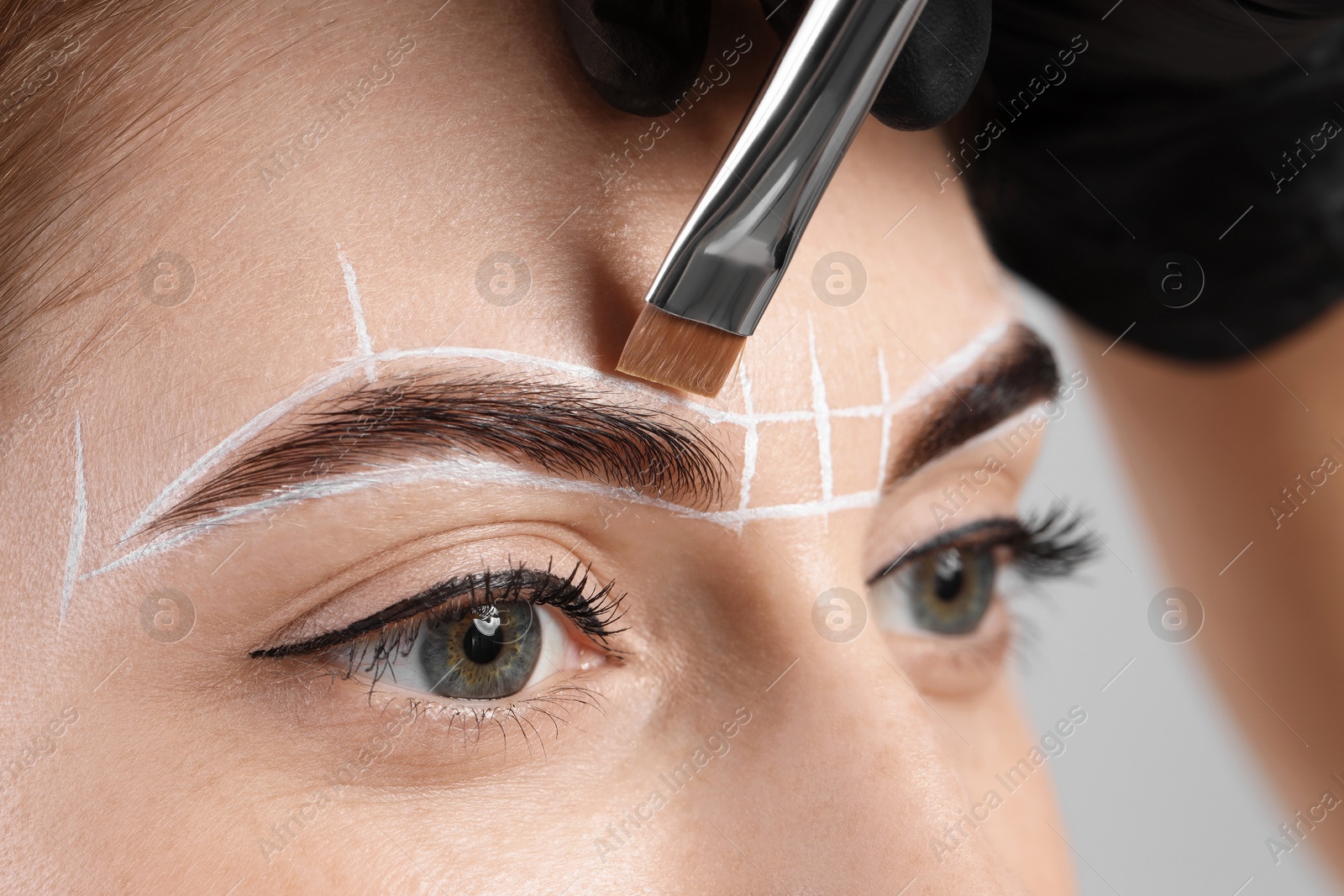 Photo of Young woman undergoing henna eyebrows dyeing procedure, closeup