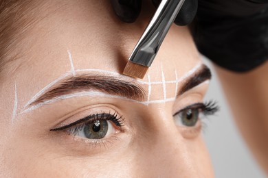 Photo of Young woman undergoing henna eyebrows dyeing procedure, closeup