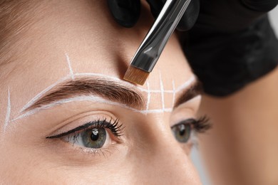 Photo of Young woman undergoing henna eyebrows dyeing procedure, closeup