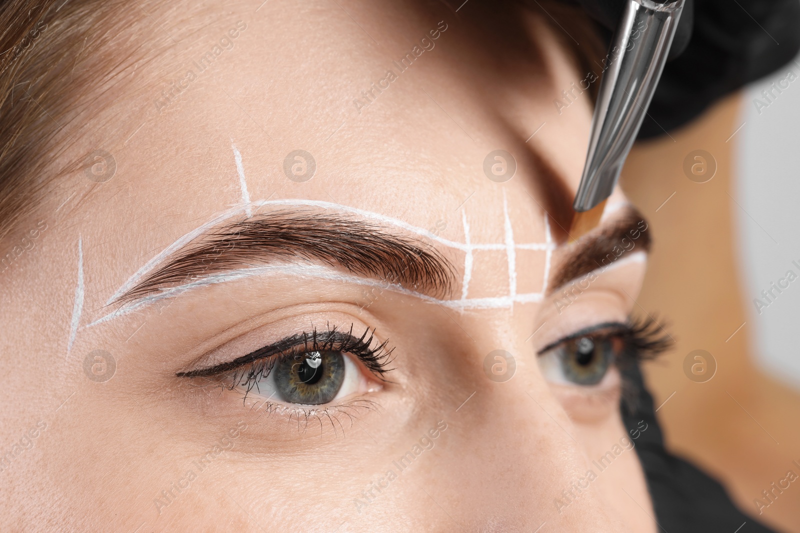 Photo of Young woman undergoing henna eyebrows dyeing procedure, closeup