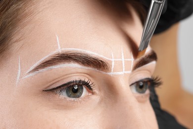 Photo of Young woman undergoing henna eyebrows dyeing procedure, closeup