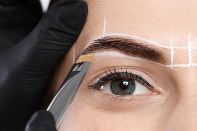 Photo of Young woman undergoing henna eyebrows dyeing procedure, closeup