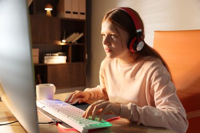 Girl playing video game with keyboard and mouse at table indoors