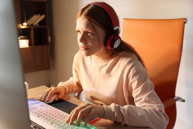 Photo of Girl playing video game with keyboard and mouse at table indoors