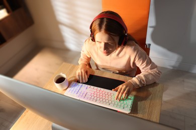 Photo of Girl playing video game with keyboard and mouse at table indoors