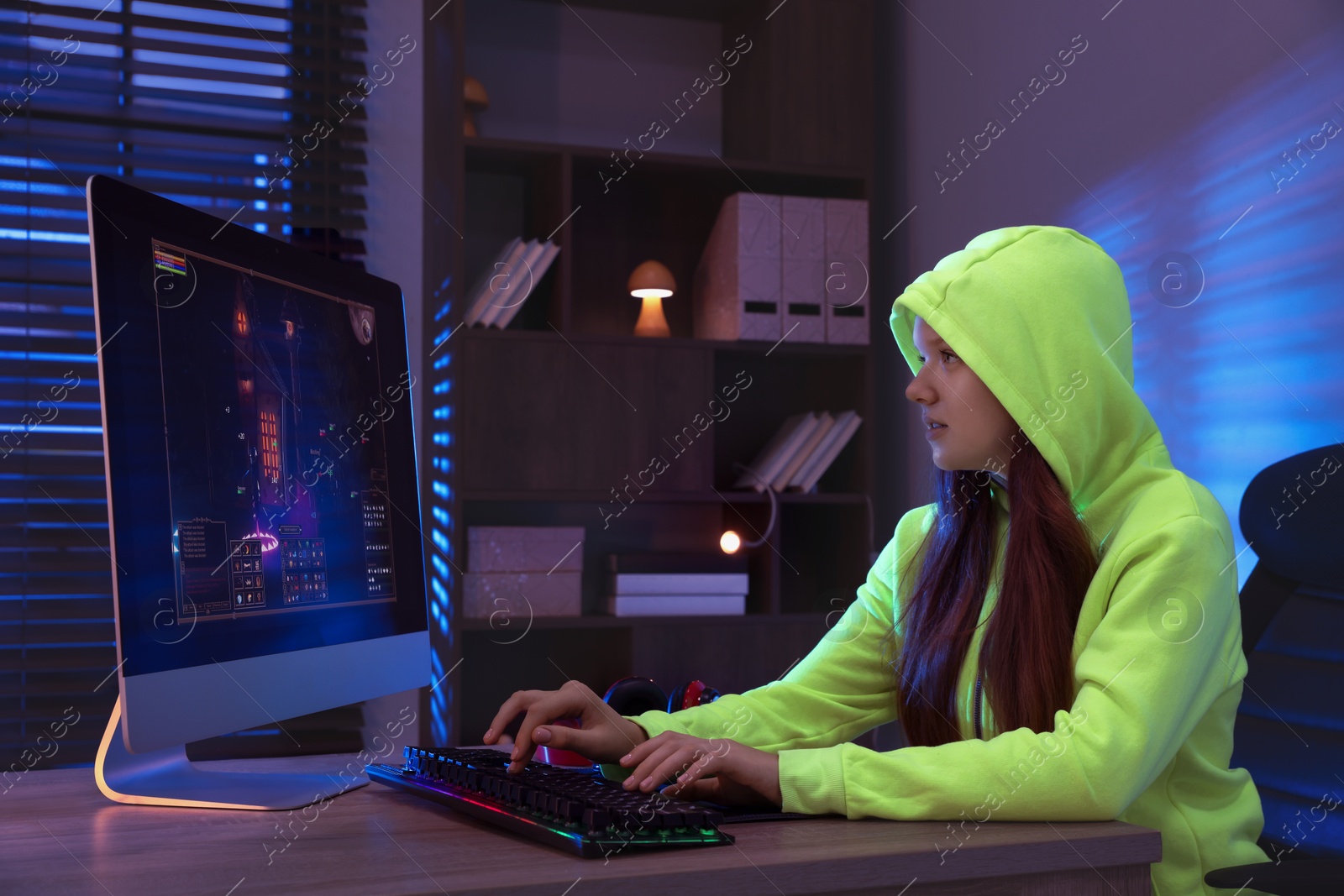 Photo of Girl playing video game with keyboard at table indoors