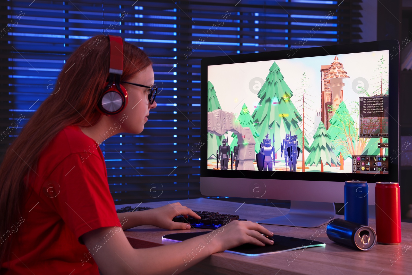 Photo of Girl playing video game with keyboard and mouse at table in dark room