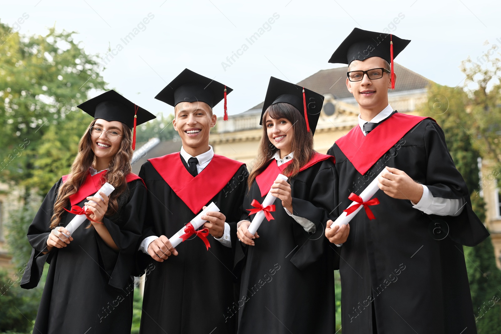 Photo of Happy students with diplomas after graduation ceremony outdoors