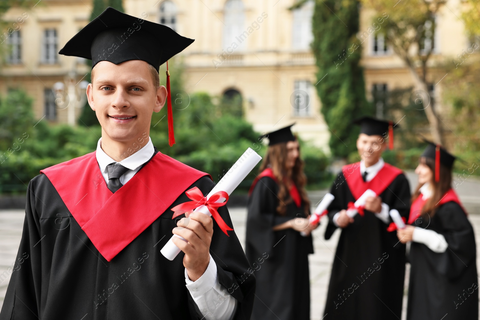 Photo of Happy students with diplomas after graduation ceremony outdoors, selective focus