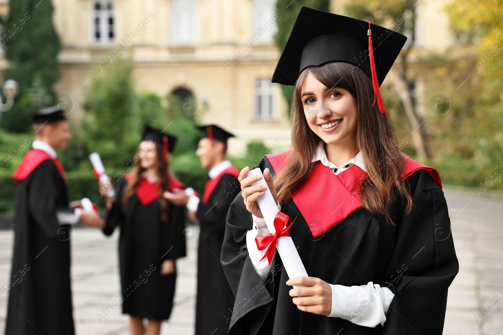 Photo of Happy students with diplomas after graduation ceremony outdoors, selective focus