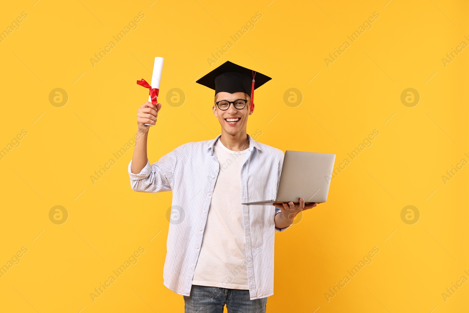 Photo of Happy student with diploma and laptop after graduation on orange background