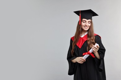 Photo of Happy student with diploma after graduation on grey background. Space for text