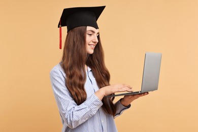 Photo of Happy student with laptop after graduation on beige background