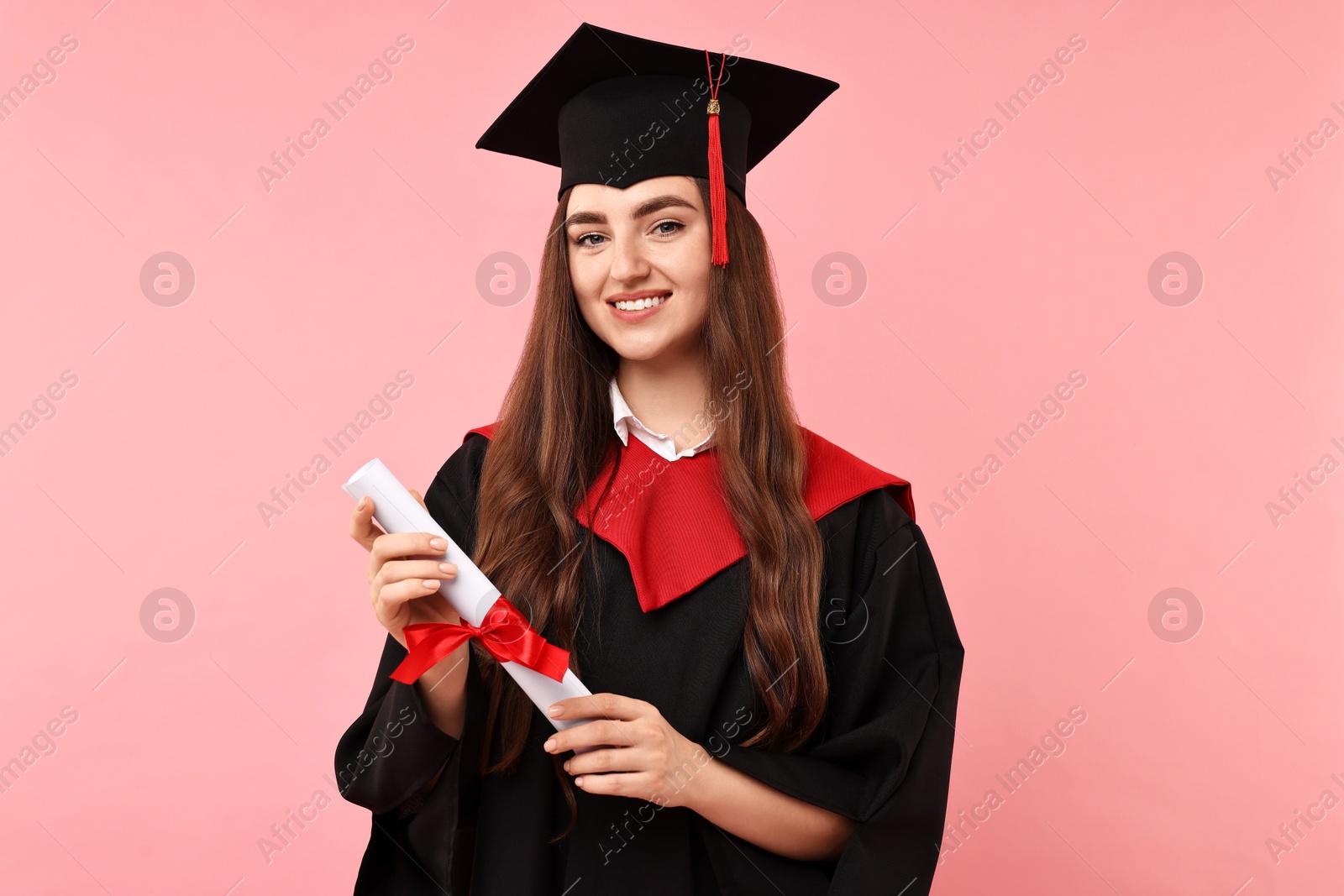 Photo of Happy student with diploma after graduation on pink background