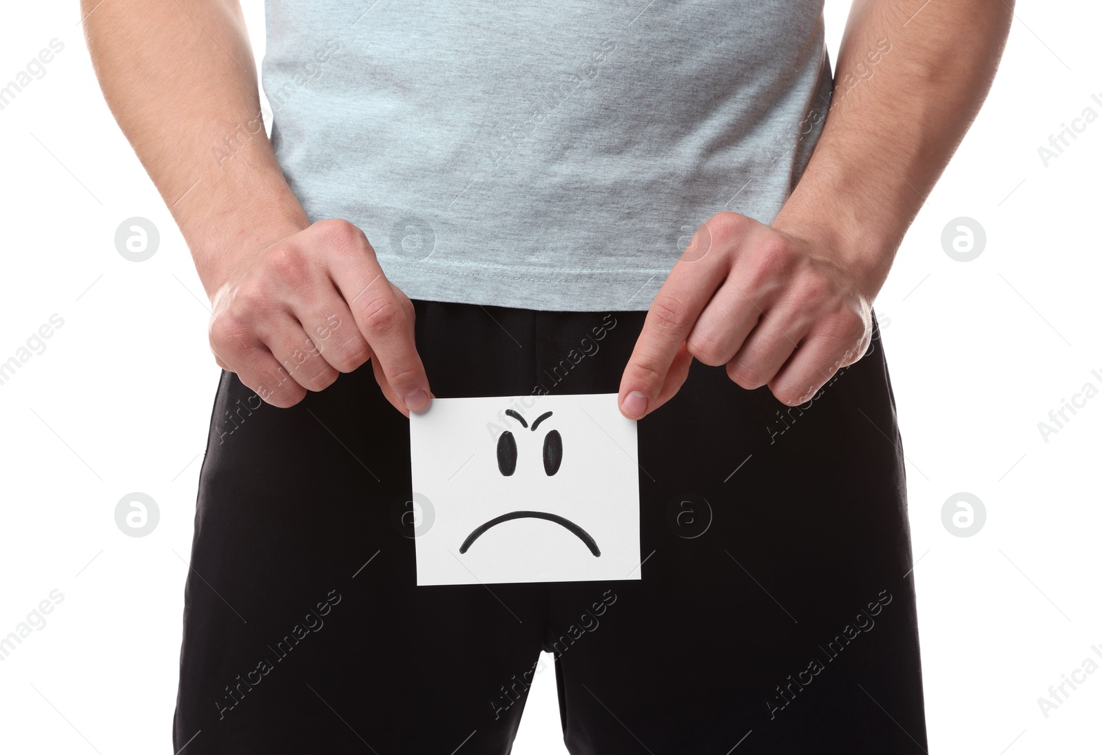 Photo of STD (sexually transmitted diseases). Man holding sticky note with drawn angry face on white background, closeup