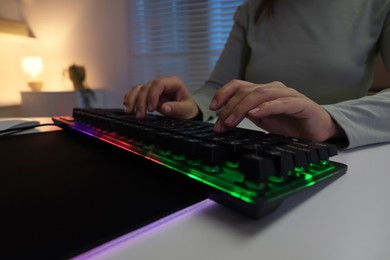 Woman using computer keyboard at white table indoors, closeup