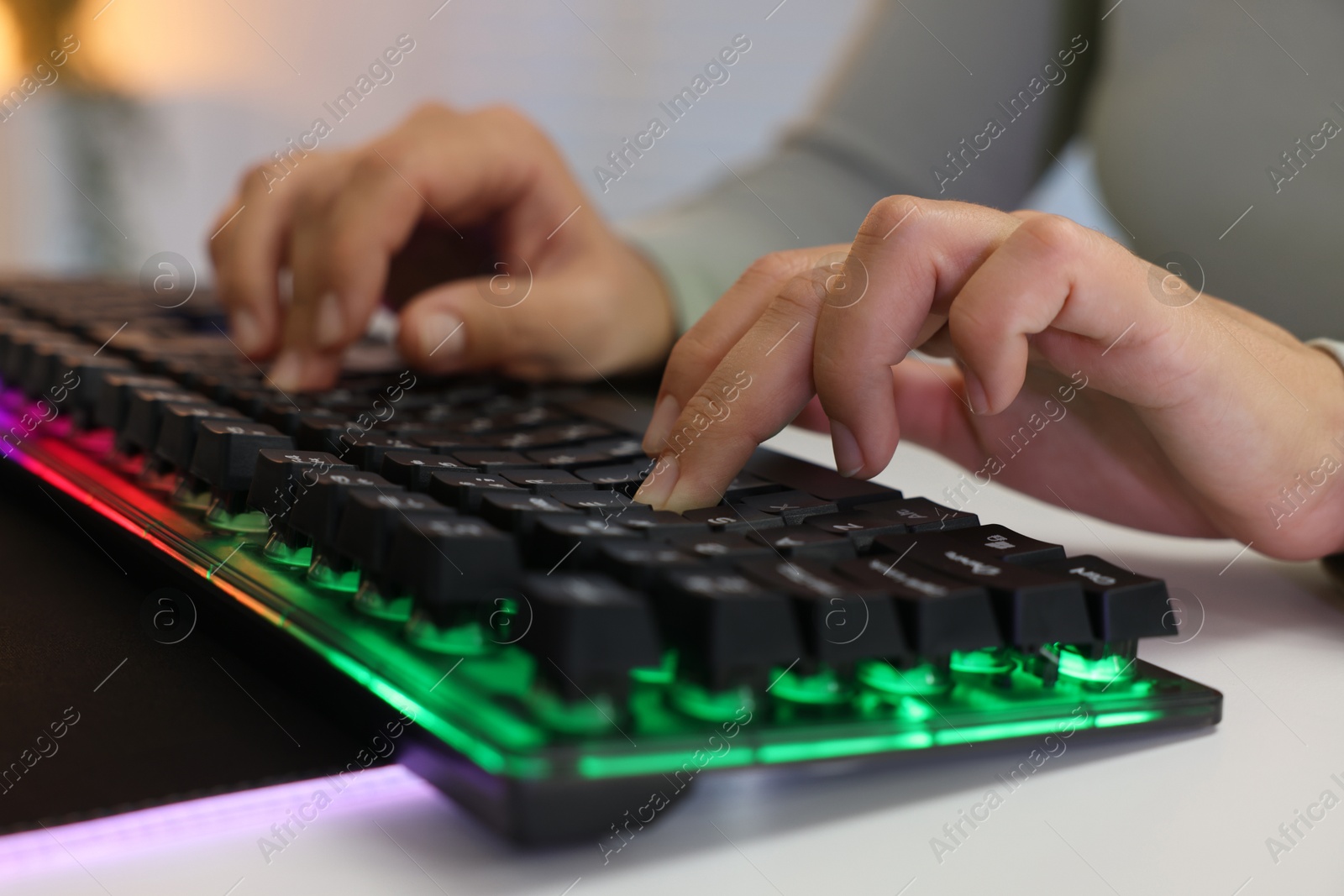 Photo of Woman using computer keyboard at white table indoors, closeup