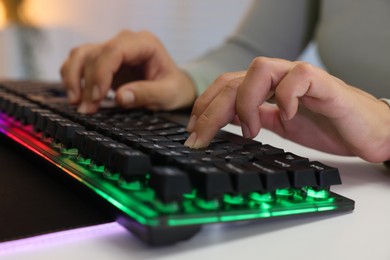 Woman using computer keyboard at white table indoors, closeup