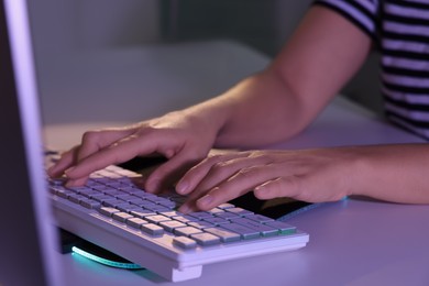 Photo of Woman using computer keyboard at white table indoors, closeup