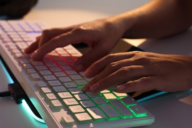 Photo of Woman using computer keyboard at white table indoors, closeup