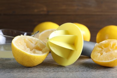 Photo of Plastic juicer and fresh lemons on grey wooden table, closeup