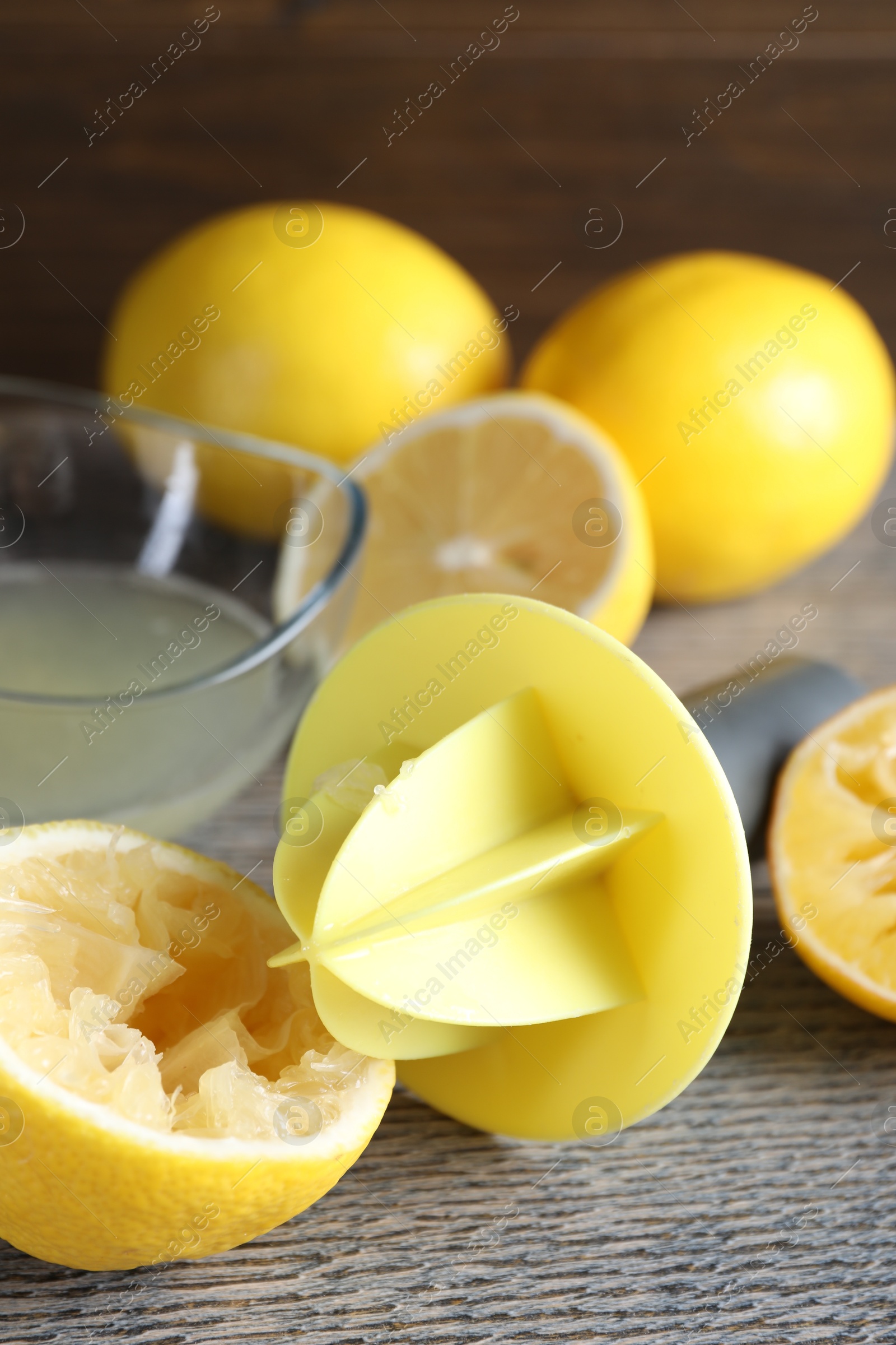 Photo of Plastic juicer and fresh lemons on grey wooden table, closeup