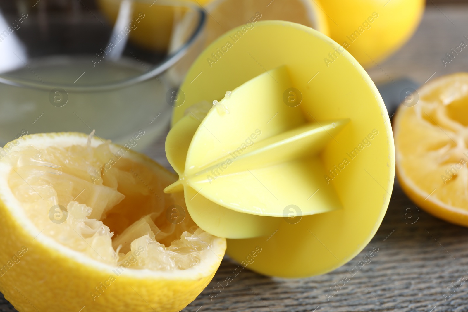 Photo of Plastic juicer and fresh lemons on grey wooden table, closeup