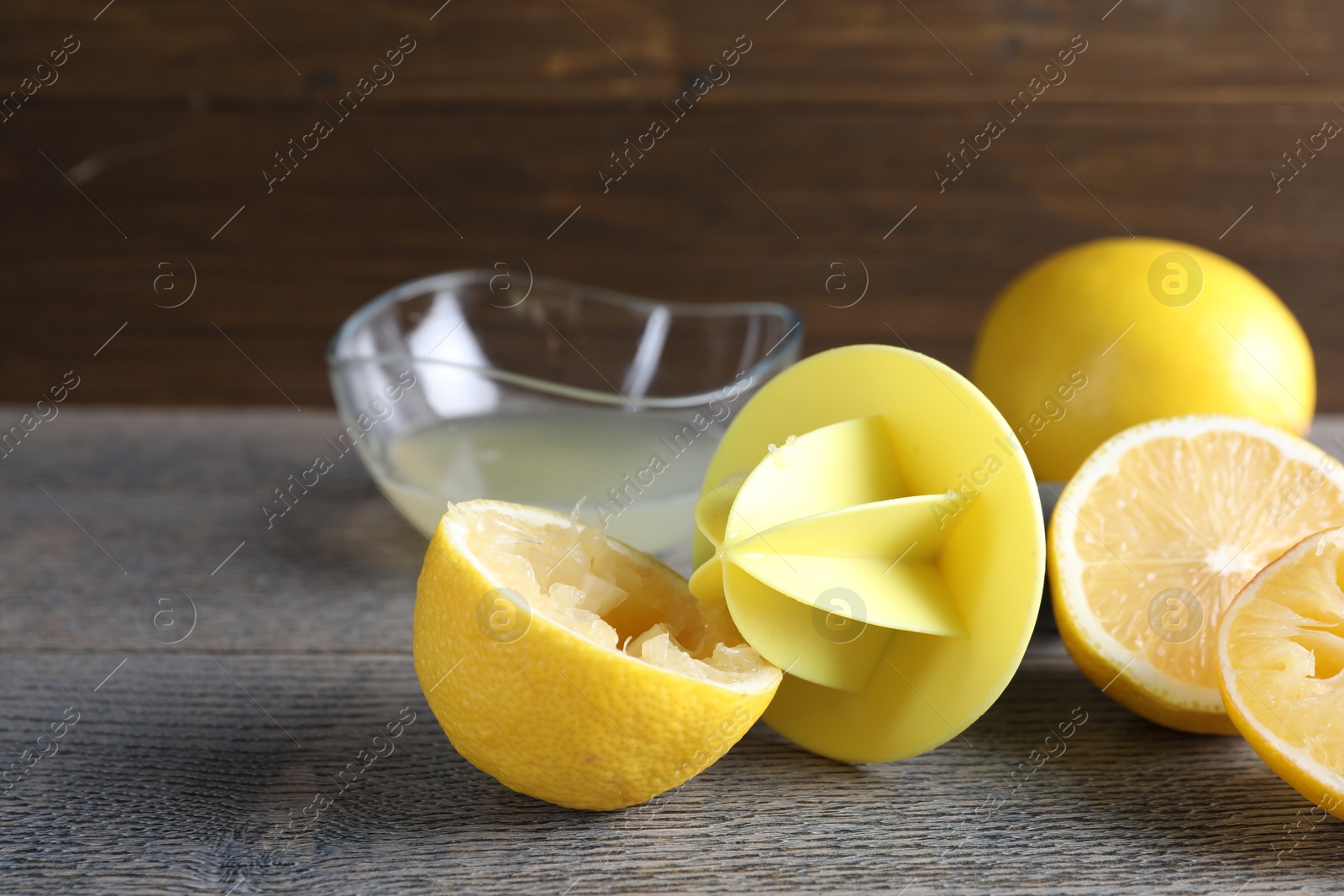 Photo of Plastic juicer and fresh lemons on grey wooden table, closeup