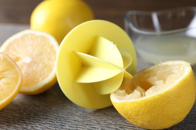 Photo of Plastic juicer and fresh lemons on grey wooden table, closeup