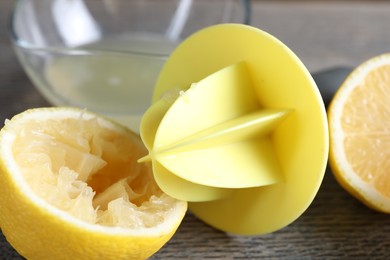 Photo of Plastic juicer and fresh lemons on grey wooden table, closeup