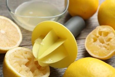 Photo of Plastic juicer and fresh lemons on grey wooden table, closeup