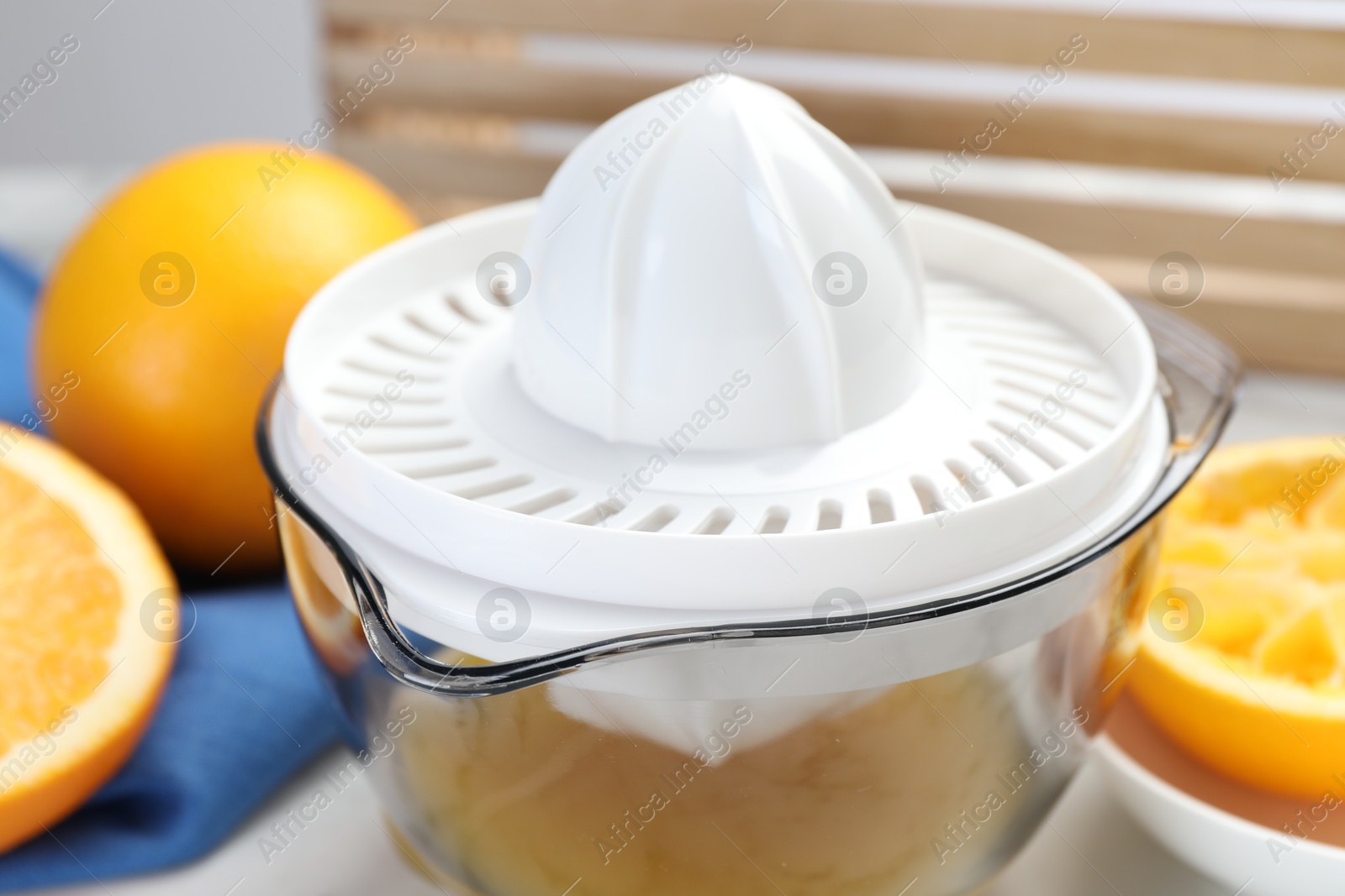 Photo of Plastic juicer and fresh oranges on white table, closeup