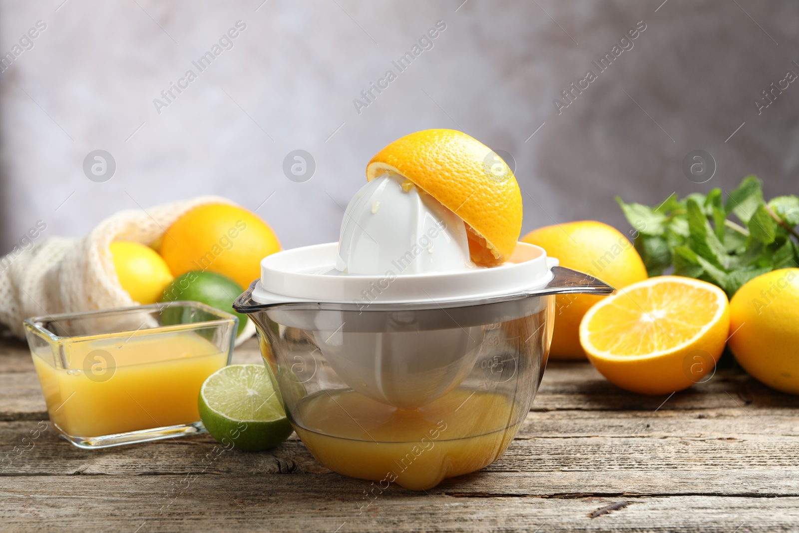 Photo of Plastic juicer and fresh oranges on wooden table, closeup