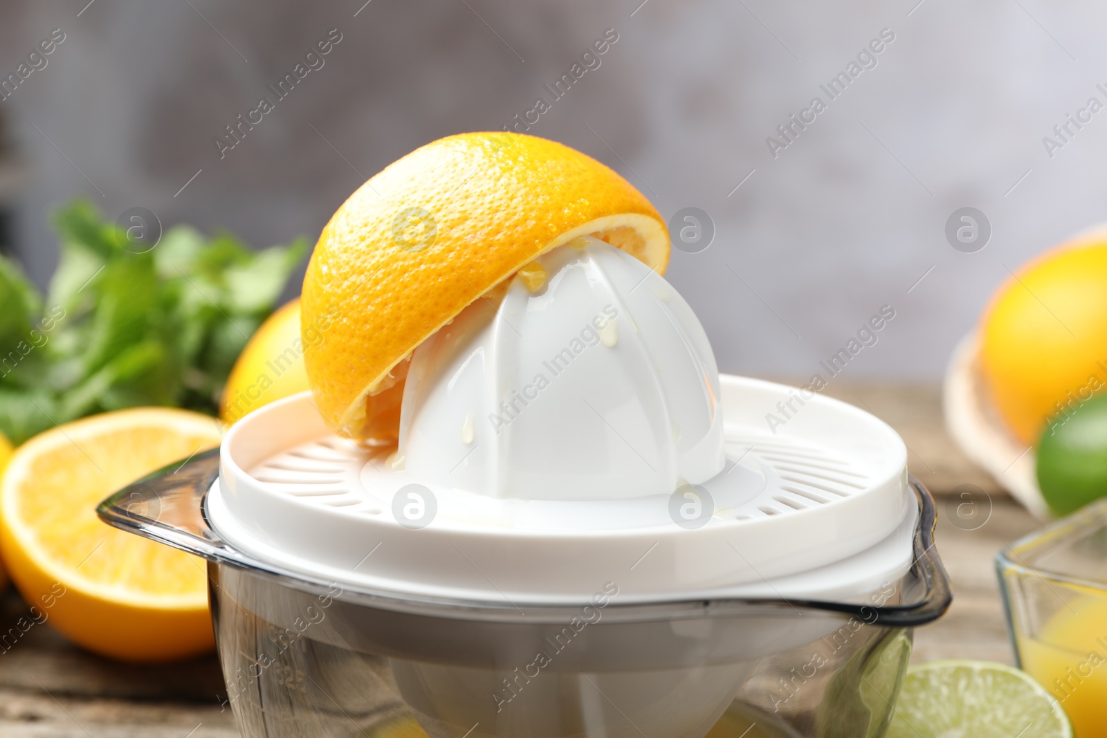 Photo of Plastic juicer and fresh oranges on wooden table, closeup